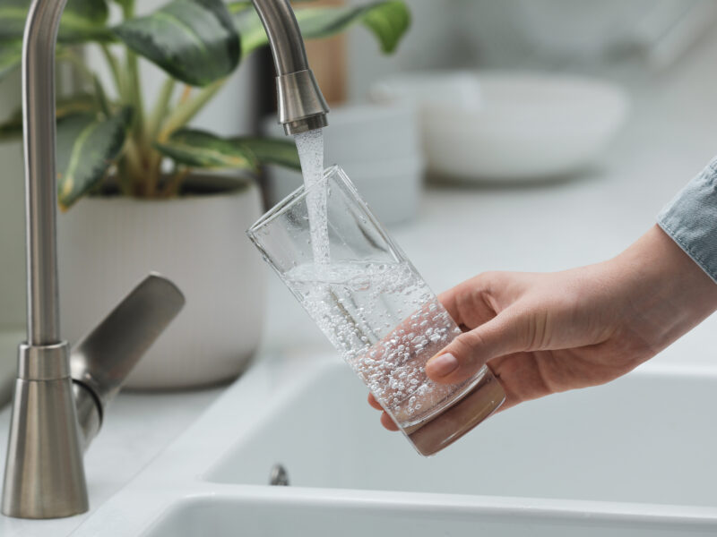 Woman,Filling,Glass,With,Water,From,Tap,In,Kitchen,,Closeup